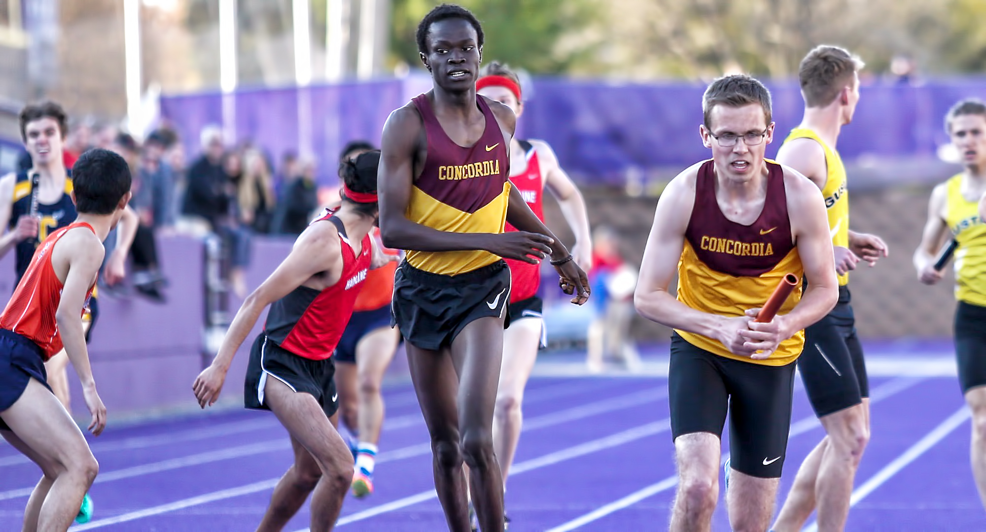 Munir Isahak hands the baton to Nolan Christenson in the 4x800-meter relay on Day 1 at the MIAC Outdoor Championship Meet. (photo courtesy of Nathan Lodermeier)