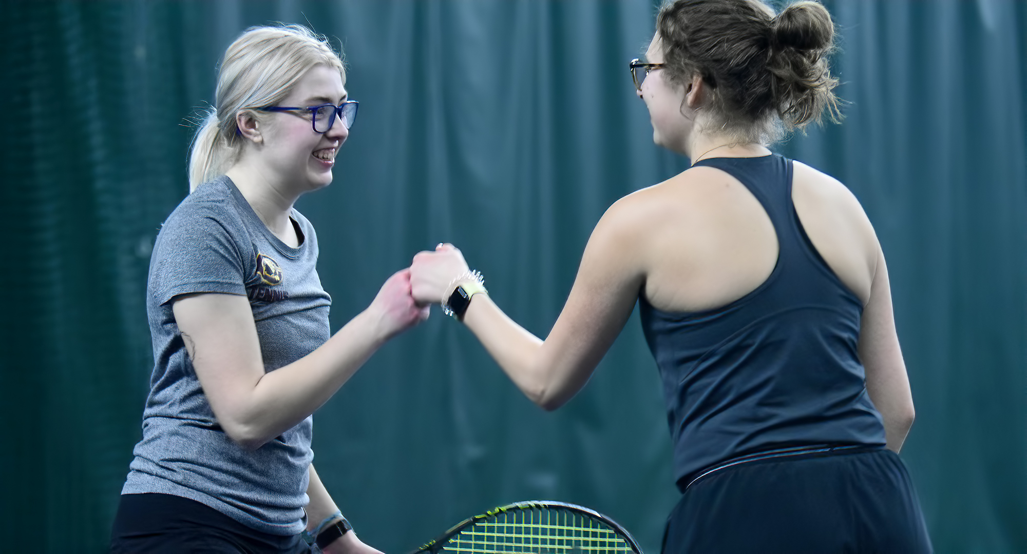 Lizzia Allan (L) and Anna Hacker celebrate winning a point in their No.2 doubles match against UW-Superior. They won 8-5 and are 3-3 on the year.