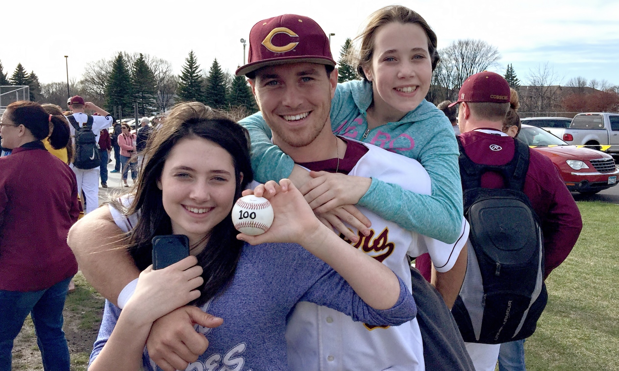 Senior Jordan Domine poses with his sisters and the ball he hammered over the left field fence for his 100th career hit in the Cobbers' sweep over Macalester.