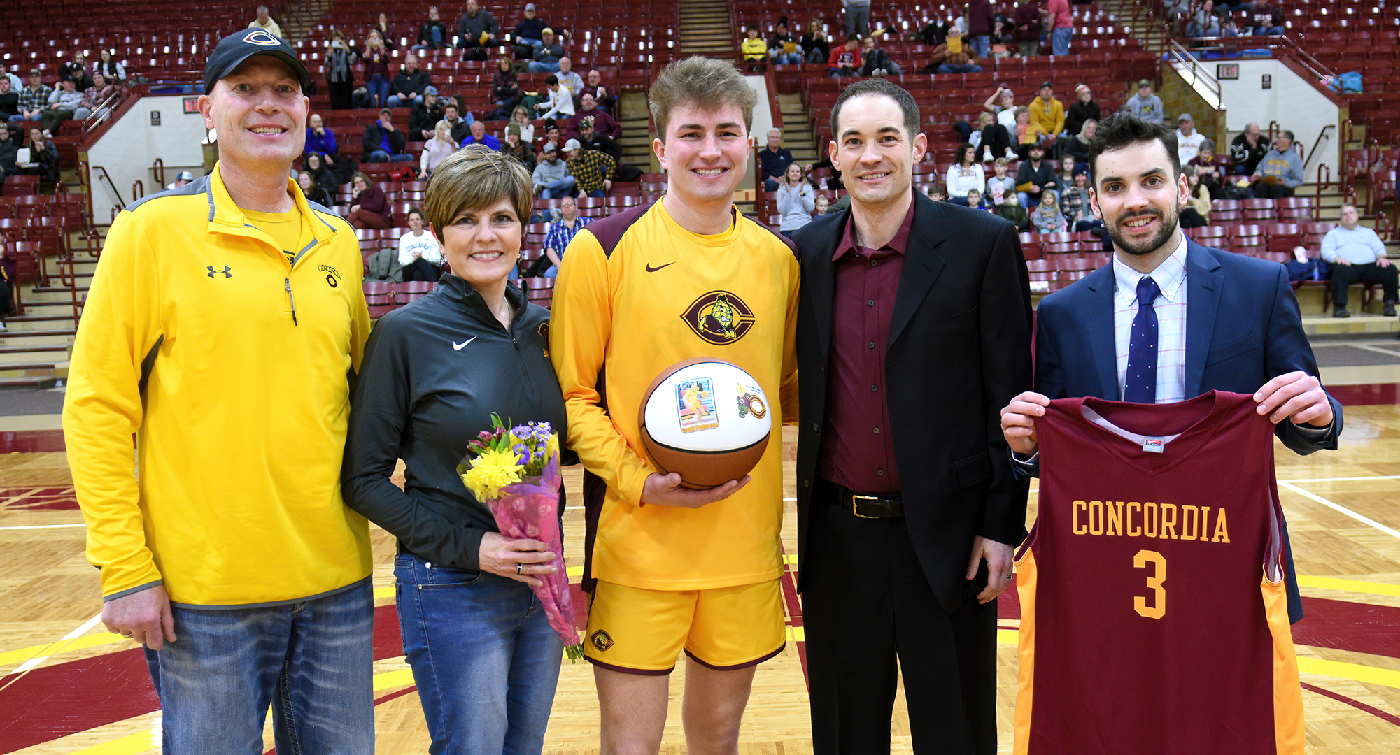 Grant Pederson and his parents were honored by head coach Tyler Bormann and assistant TJ Lake before the Cobbers' game with Augsburg.
