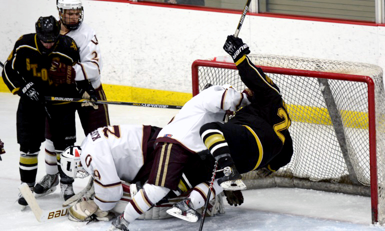 Cobber defenseman Bryan Kronberger takes a St. Olaf player to the ice in order to protect goalie Jordyn Kaufer.