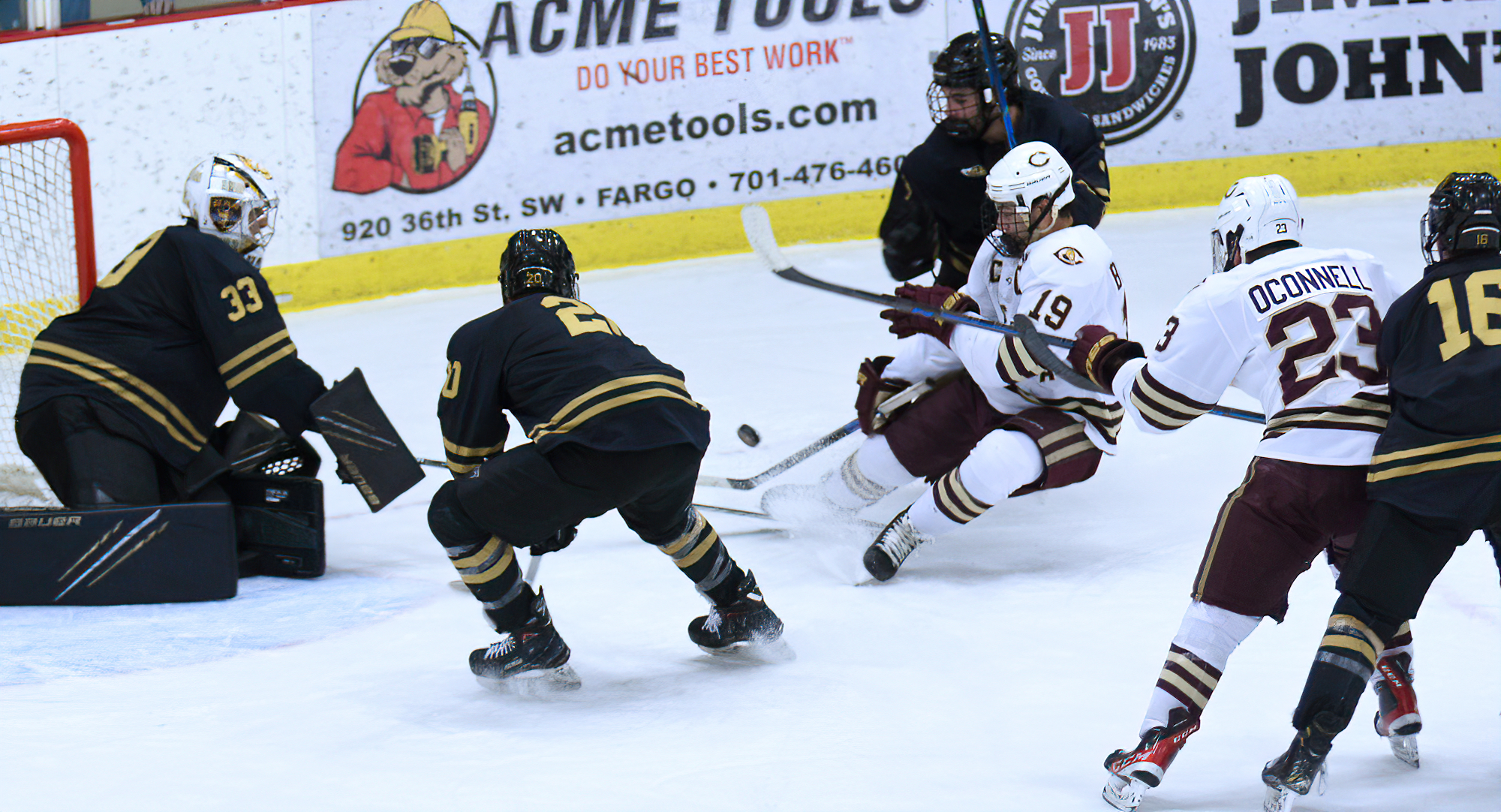 Tyler Bossert is hauled to the ice by a St. Olaf defender during the Cobbers' playoff game. Bossert recorded his 100th career point in the contest.