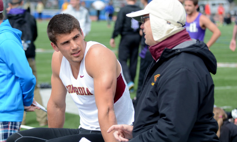 Brandon Zylstra talks with head coach Garrick Larson during the long jump at the MIAC Meet. He went on to win the event.
