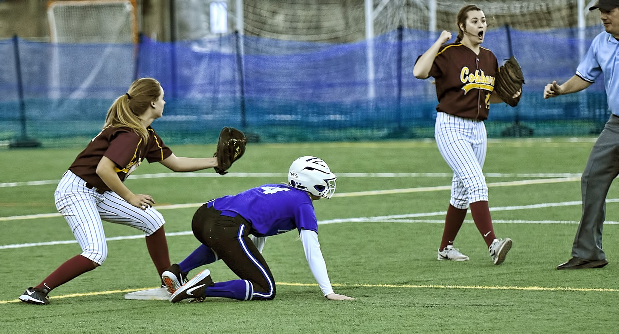 Shortstop Maria Pake show the umpire the ball after making a tag on a would-be stolen base attempt in the Cobbers' first game with Finlandia. Second baseman Kate Wensloff is helping the umpire make the call.
