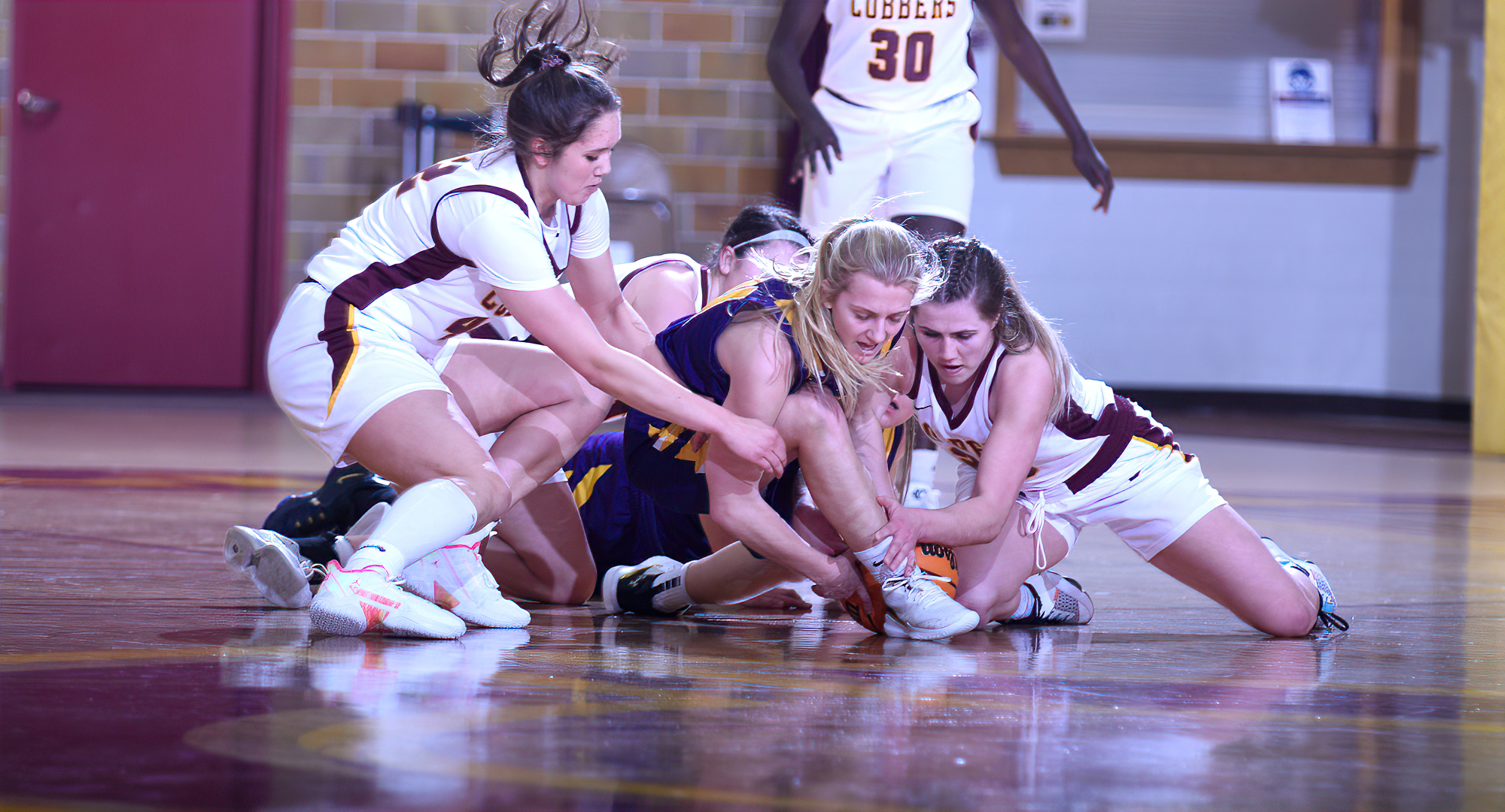 Makayla Anderson (L) and Emily Beseman (Far Right) lead a group of Cobbers fighting for a loose ball during their playoff game with St. Catherine.