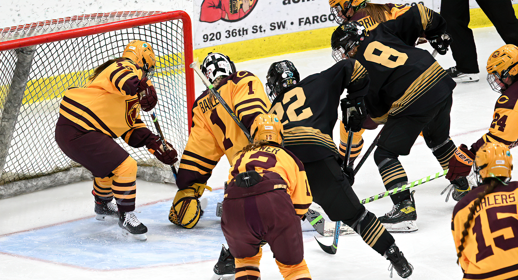 Lila Lanctot (far left) reaches behind goalie Hailee Bailey to stop the puck from crossing the goal line during the Cobbers' game with St. Olaf.