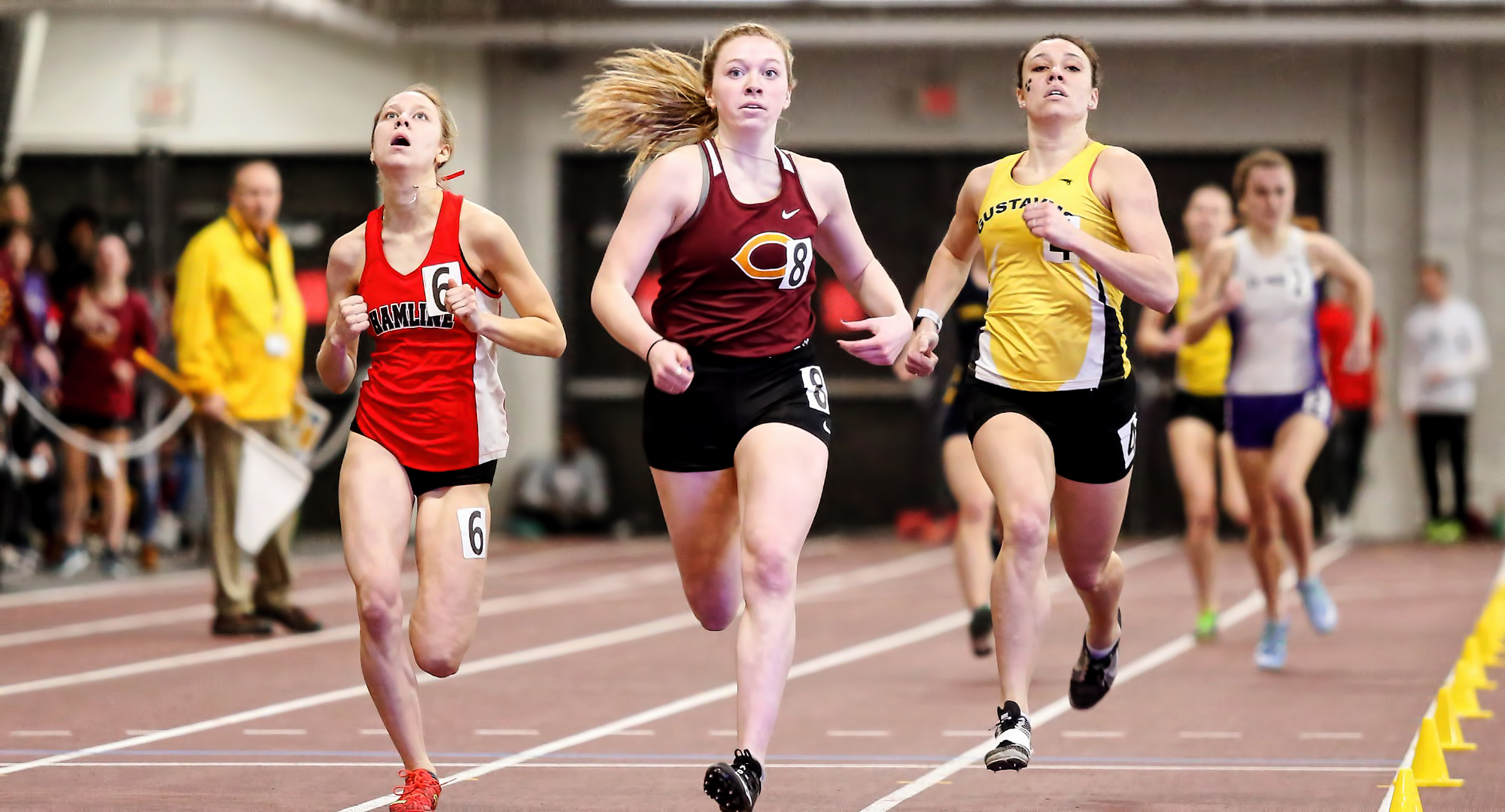 Sophomore Josie Herrmann crosses the finish line a mere .15 of a second ahead of the runner from Hamline to win the 1000 meters at the MIAC Indoor Meet. (Photo courtesy of Nathan Lodermeier)