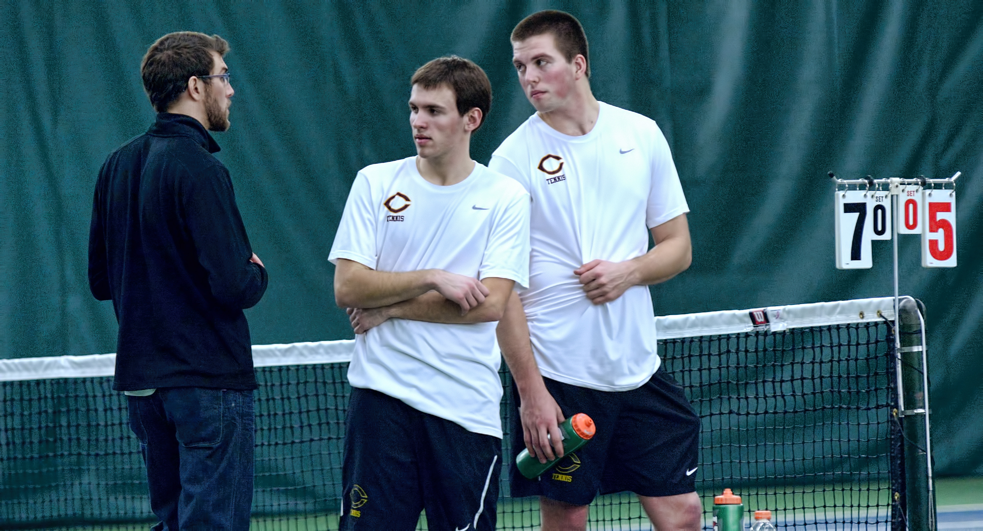 The Cobber No.1 doubles team of David Youngs (L) and Isaac Toivonen talk with head coach Joseph Murrey. The tandem won their bout at No.1 doubles and both players claimed singles wins in CC's 5-4 win at St. Mary's.