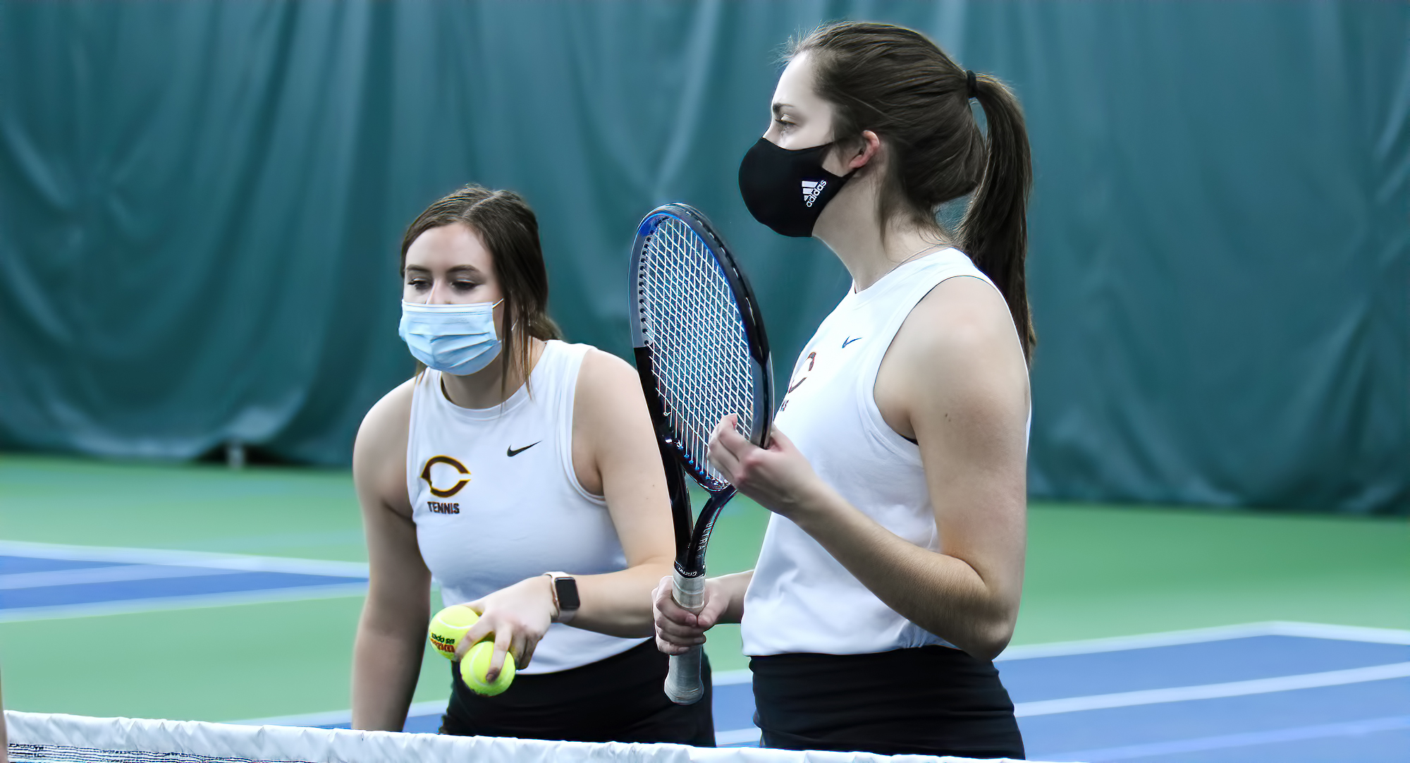 Abby Westrum (L) and Taylor Partington go over pre-match instructions at the net before their doubles match on Sunday against Bethel.