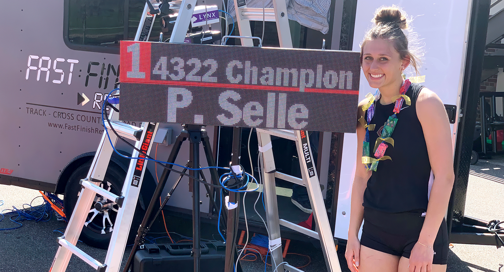 Peyton Selle poses next to the electronic timing board after winning her second consecutive MIAC heptathlon championship.
